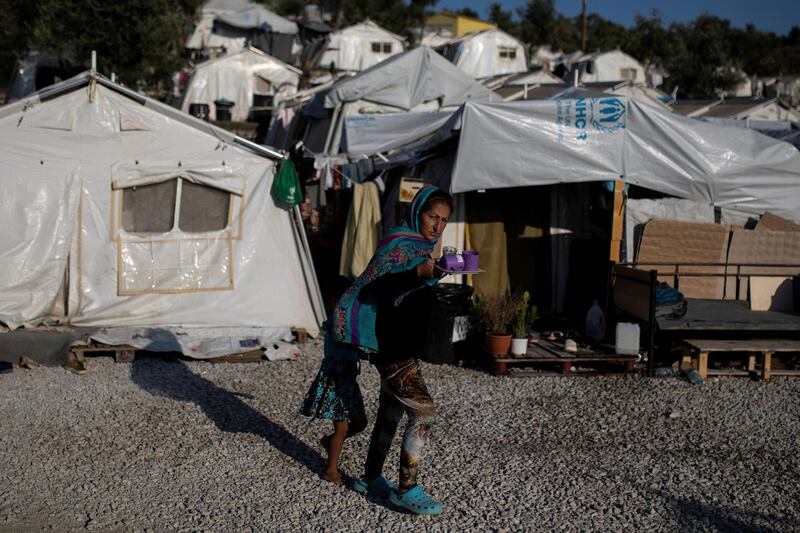 FILE PHOTO: A migrant from Afghanistan and her daughter make their way at a makeshift camp for refugees and migrants next to the Moria camp on the island of Lesbos, Greece, September 1, 2019. REUTERS/Alkis Konstantinidis/File Photo