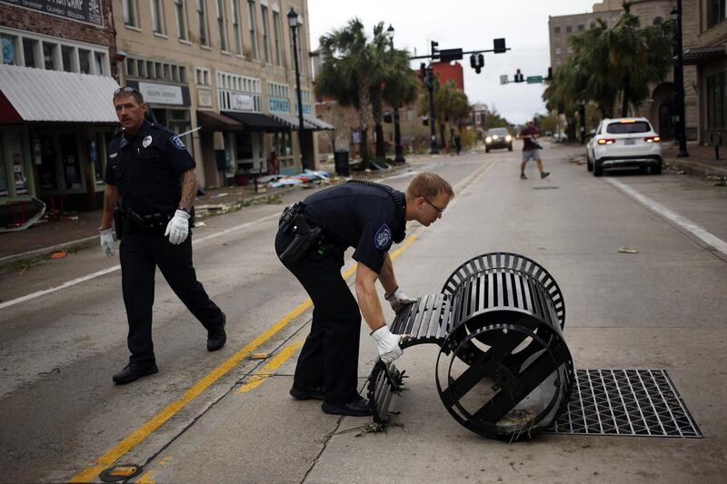 A police officer picks up a trash can in the street after Hurricane Laura made landfall in Lake Charles, Louisiana. Bloomberg