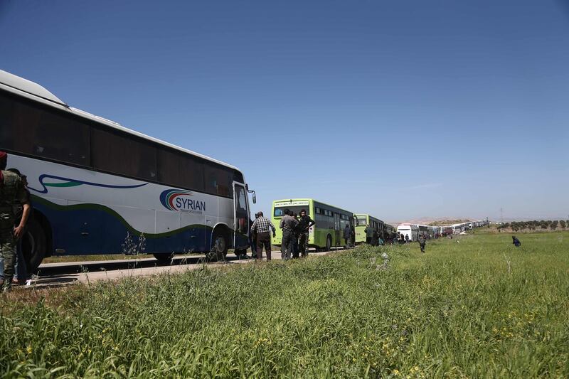 A convoy transporting Syrian civilians and rebel fighters evacuated from Eastern Ghouta waits in a government-held area prior to entering the village of Qalaat al-Madiq, some 45 kilometres northwest of the central city of Hama, on March 26, 2018, as evacuations from the opposition enclave continued following a deal that was announced earlier in the week. Abdulmonam Eassa / AFP