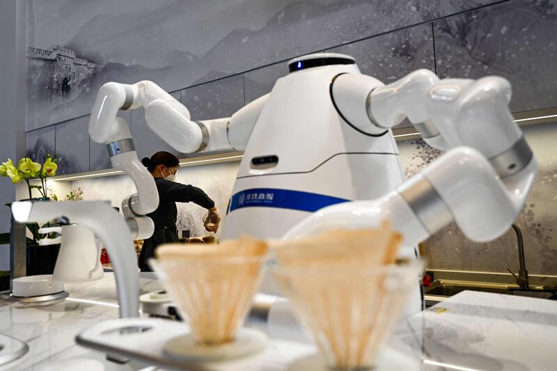 An attendant pours coffee as a robot makes a fresh pot in a waiting area within the closed-loop ‘bubble’ at the Taizicheng train station in Zhangjiakou ahead of the 2022 Beijing Winter Olympic Games. AFP