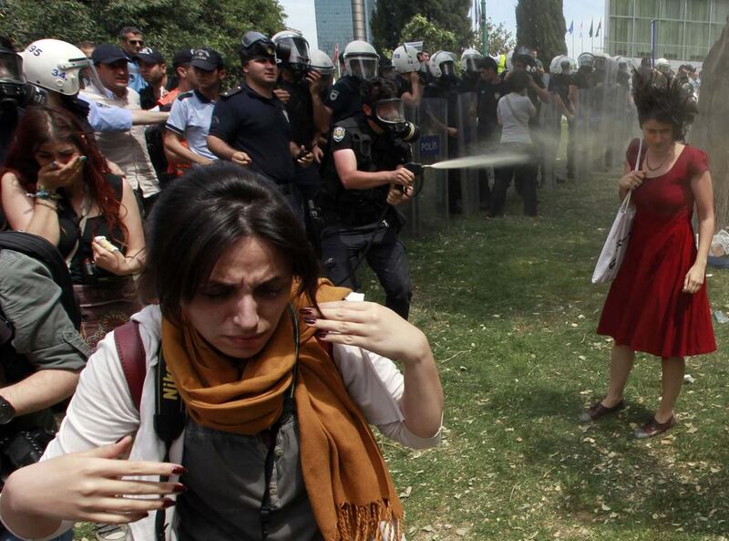 A Turkish riot policeman uses tear gas as people protest against the destruction of trees in a park brought about by a pedestrian project, in Taksim Square in central Istanbul on May 28, 2013. Osman Orsal / Reuters