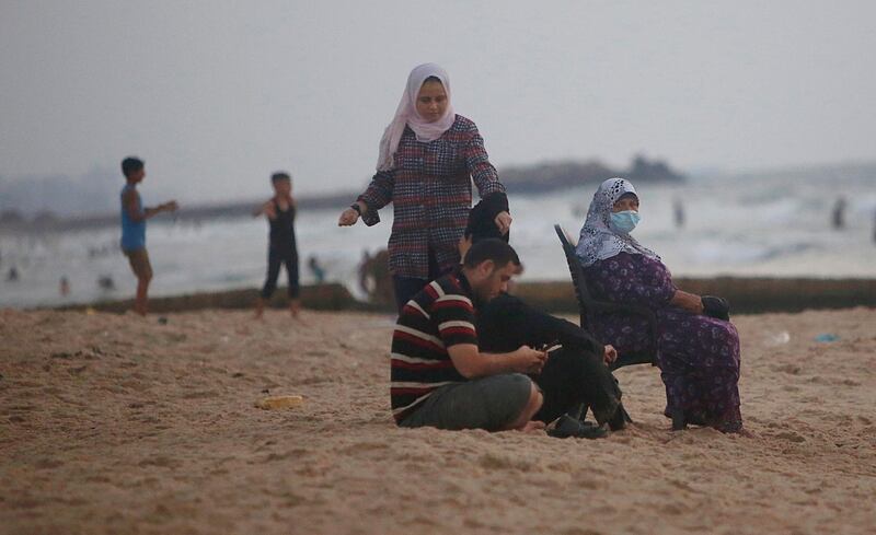 A Palestinian woman wears a face mask as she sits on the beach of the Mediterranean sea in Gaza City. AP Photo
