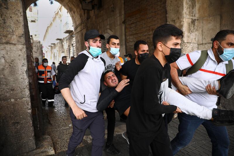 Palestinians carry a wounded protester at the Lions' Gate in Jerusalem's Old City, on Monday, May 10, 2021. AP