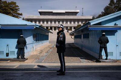 TOPSHOT - A South Korean soldier (C) stands guard before the military demarcation line and North Korea's Panmun Hall, in the truce village of Panmunjom, within the Demilitarized Zone (DMZ) dividing the two Koreas on February 21, 2018. / AFP PHOTO / Ed JONES