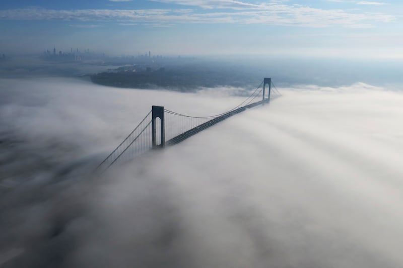 The Manhattan skyline is visible, upper left, as cars traverse the Verrazzano-Narrows Bridge, connecting the Brooklyn and Staten Island boroughs of New York, while fog covers the waters of the Atlantic Ocean and New York Bay. AP