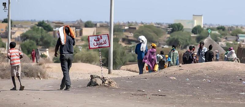 Refugees walk through Hamdiyet border crossing point without pausing at the "stop for inspection" sign in Arabic. Credit : Hussein Saleh Ary