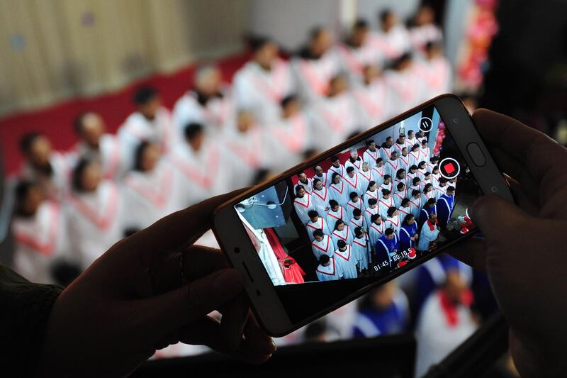This photo, taken on December 24, 2017, shows a participant taking a video as a choir sings hymns during a Christmas Eve mass at a church in Fuyang in China's eastern Anhui province. AFP
