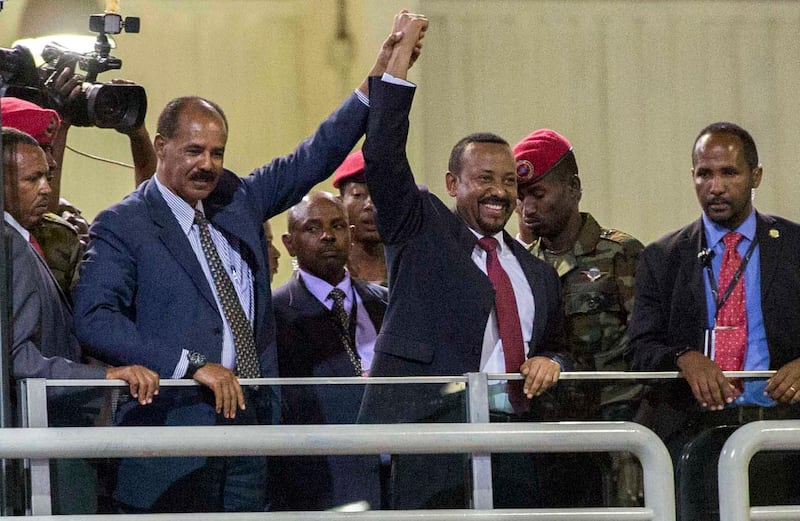 Eritrean President Isaias Afwerki, second left, and Ethiopia's Prime Minister Abiy Ahmed, center, hold hands as they wave at the crowds in Addis Ababa, Ethiopia, Sunday July 15, 2018. Official rivals just weeks ago, the leaders of Ethiopia and Eritrea have embraced warmly to the roar of a crowd of thousands at a concert celebrating the end of a long state of war. A visibly moved Eritrean President Isaias Afwerki, clasping his hands over his heart, addressed the crowd in Ethiopia's official language, Amharic, on his first visit to the country in 22 years. (AP Photo/Mulugeta Ayene)