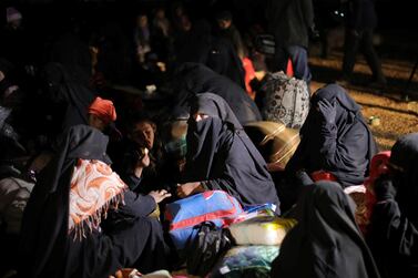 Women sit together with their belongings near the village of Baghouz. Reuters 