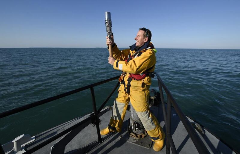 Jason Norman, Skipper of the St Peter Port Lifeboat 'Spirit of Guernsey', holds the Queen's Baton as it heads to the island of Alderney during the Glasgow 2014 Baton Relay in Guernsey. Ben Birchall / Glasgow 2014 Ltd via Getty Images