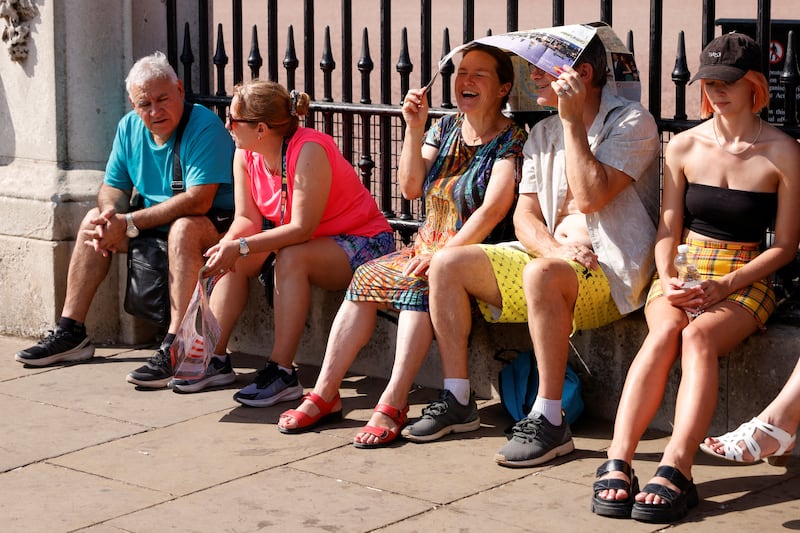 People use a map to shelter from the sun outside Buckingham Palace in London. Reuters
