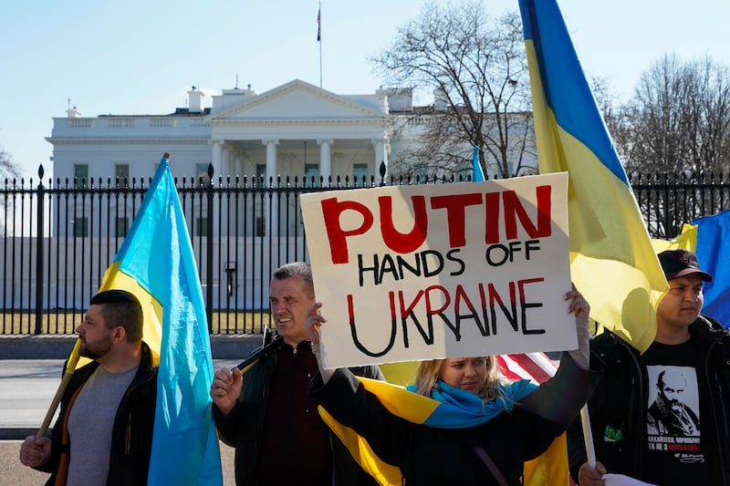 Demonstrators hold flags and a sign during a 'Stand with Ukraine' rally in front of the White House in Washington. Reuters