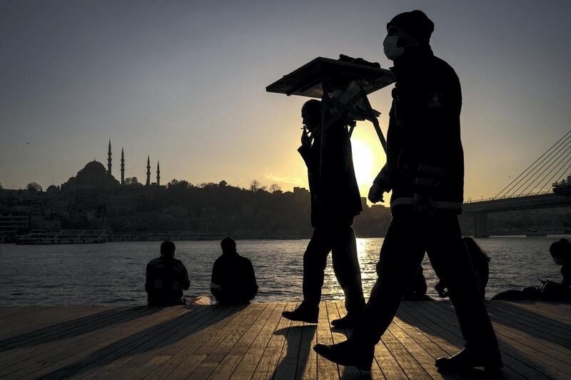 epa08920575 A street vendor selling simit pastries near Golden Horn with Suleymaniye Mosque in the background  on sunny day in Istanbul, Turkey, 05 January  2021.  EPA/SEDAT SUNA