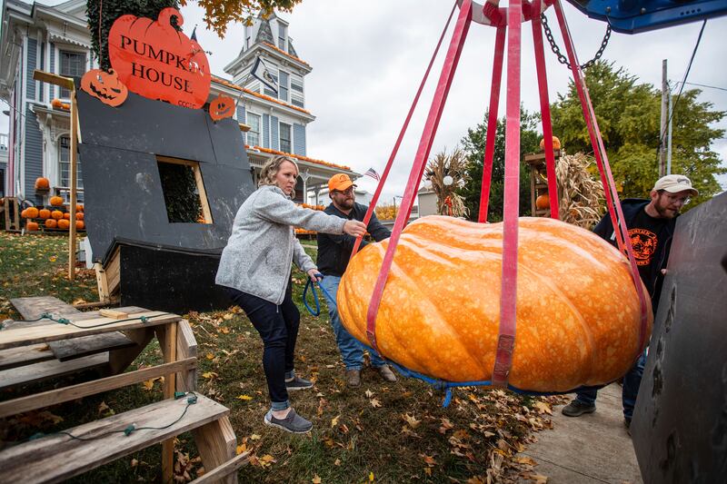Sarah Beth Baker, left, helps other volunteers position her 1,080 pound pumpkin at the Pumpkin House on Wednesday, Oct.  26, 2022, in Kenova, W. Va.  (Sholten Singer / The Herald-Dispatch via AP)