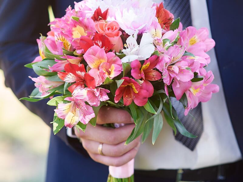 HBRXRE groom holds the brides bouquet in wedding day. Galyna Tymonko / Alamy Stock Photo