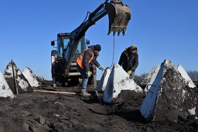 Ukrainian workers install anti-tank bulwarks, also known as dragon's teeth, at a defence line in Kharkiv region. AFP