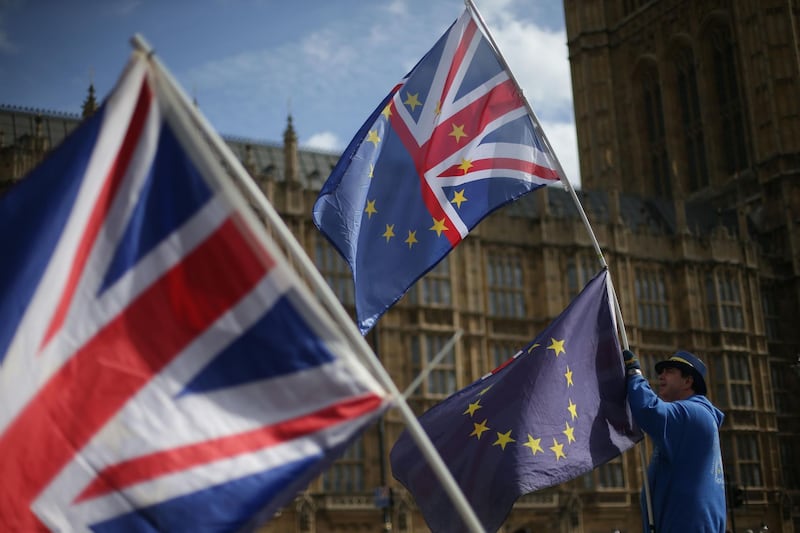 A pro-EU activist holds an EU and Union Jack flag outside of the Houses of Parliament in Westminster, central London on March 23, 2018. / AFP PHOTO / Daniel LEAL-OLIVAS