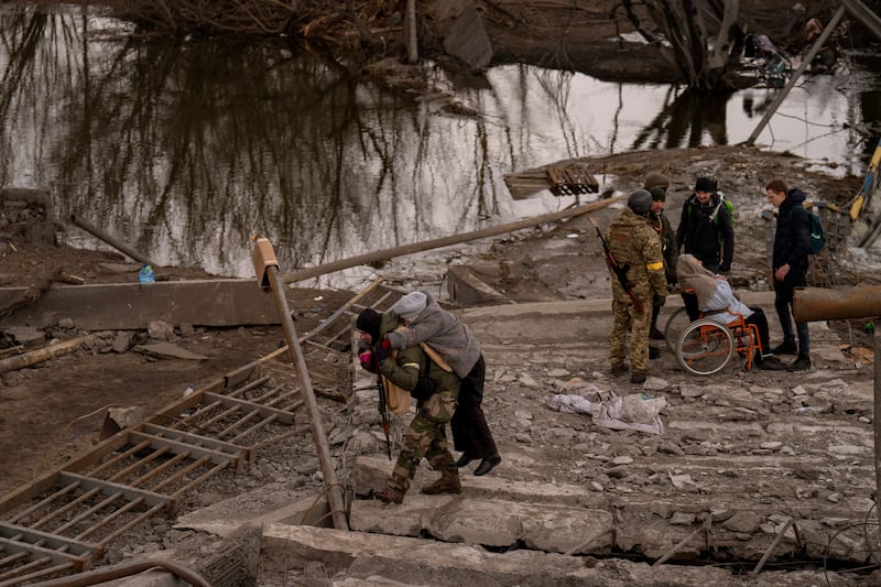 A Ukrainian soldier carries an elderly woman crossing the Irpin river on the outskirts of Kyiv. AP