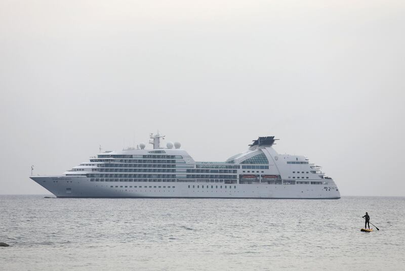 A woman paddles on a stand-up board near a cruise ship, close to the coastal city of Limassol, Cyprus. Reuters