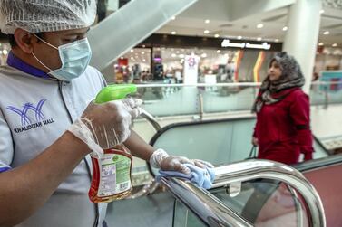 A cleaner in Khalidiyah Mall, Abu Dhabi, disinfects stainless steel railings. Victor Besa / The National 