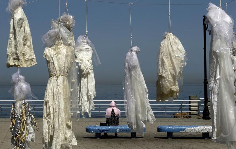 A woman sits on a bench near an installation of wedding dresses by Lebanese artist Mireille Honein and NGO Abaad at a spot along Beirut's Corniche on April 22, 2017. Patrick Baz / AFP

