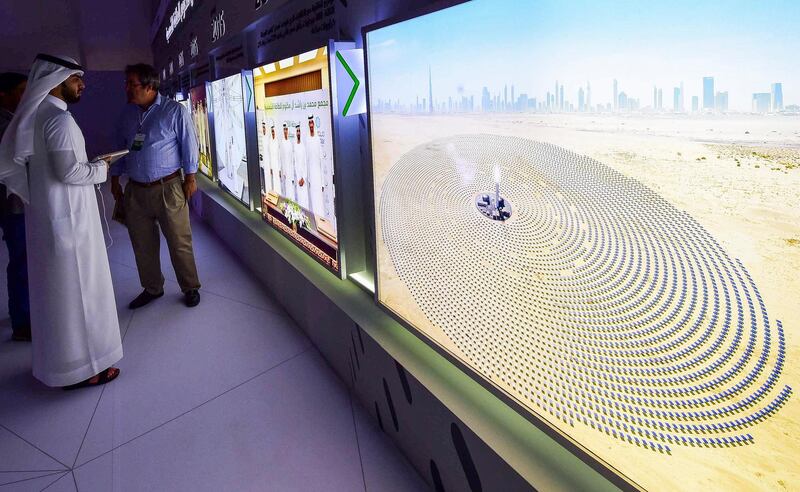 Visitors look at screens displaying images of the Mohammed bin Rashid Al-Maktoum Solar Park on March 20, 2017, at the solar plant in Dubai. - Dubai completed a solar plant big enough to power 50,000 homes as part of a plan to generate three-quarters of its energy from renewables by 2050. (Photo by STRINGER / AFP)