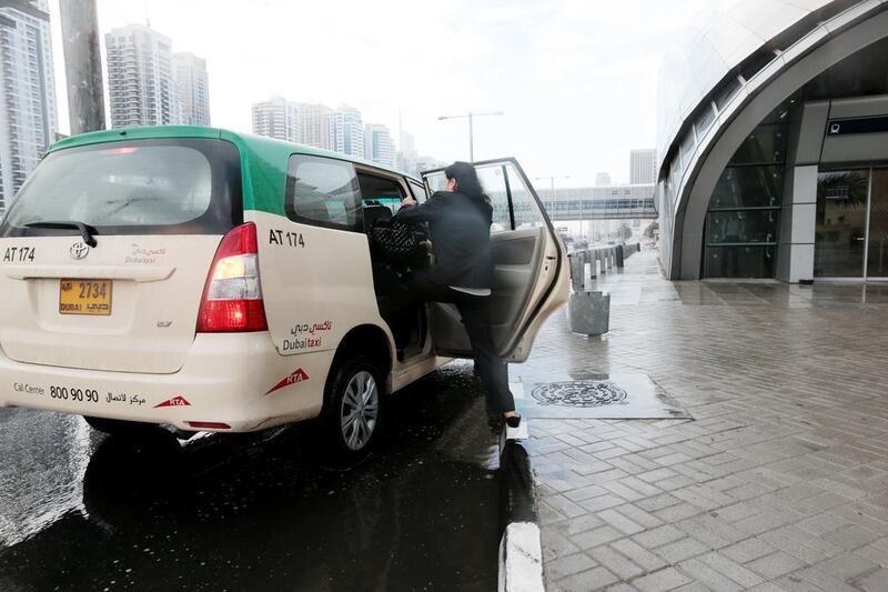  A woman lunges over a puddle to get into a taxi during a rain storm in Dubai’s Marina area. Christopher Pike / The National