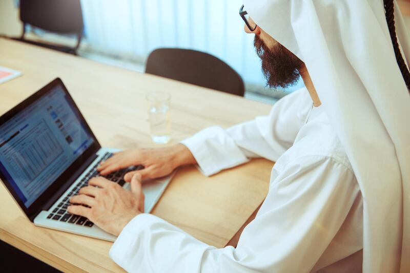 TWJRJ2 Arab saudi businessman working online with a laptop and tablet in his comfortable cabinet or office. Male model as an enterpreneur. Concept of business, finance, modern technologies, start up, economy.