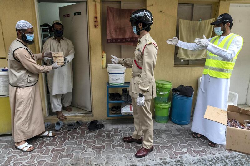 DUBAI, UNITED ARAB EMIRATES. 27 APRIL 2020. Dar Al Ber Iftar meals are handed out as part of their charity work at labour camps in Al Qouz 1. Keeping a watchfull eye is Dubai Police officers from the Bur Dubai Police Station monitoring body temperature with the new thermal helmet camera. (Photo: Antonie Robertson/The National) Journalist: None. Section: National.