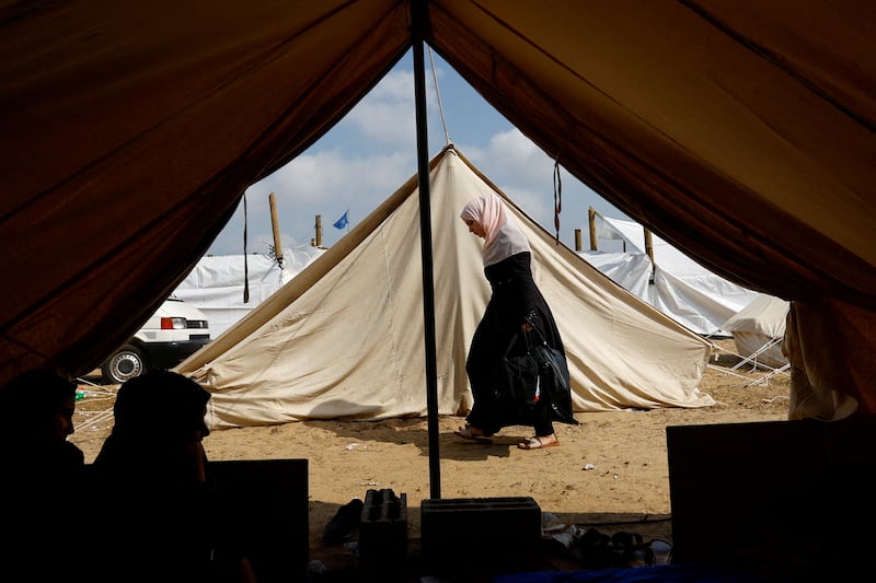 A Palestinian woman walks past tents after fleeing their homes amid Israeli strikes. Many opted to take shelter in a tent camp at a UN-run centre. Reuters