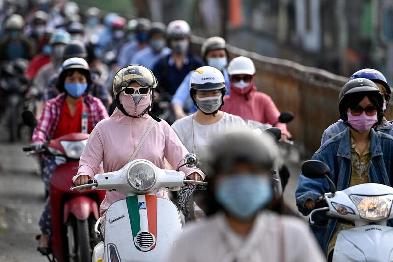 (FILES) In this file photo taken on May 4, 2021, morning commuters wearing face masks, amidst concerns about the spread of the Covid-19 coronavirus, ride past in Hanoi. Vietnam announced the discovery of a new Covid-19 variant which spreads quickly by air and is a combination of the Indian and UK strands, state media reported on May 29, 2021. / AFP / Manan VATSYAYANA
