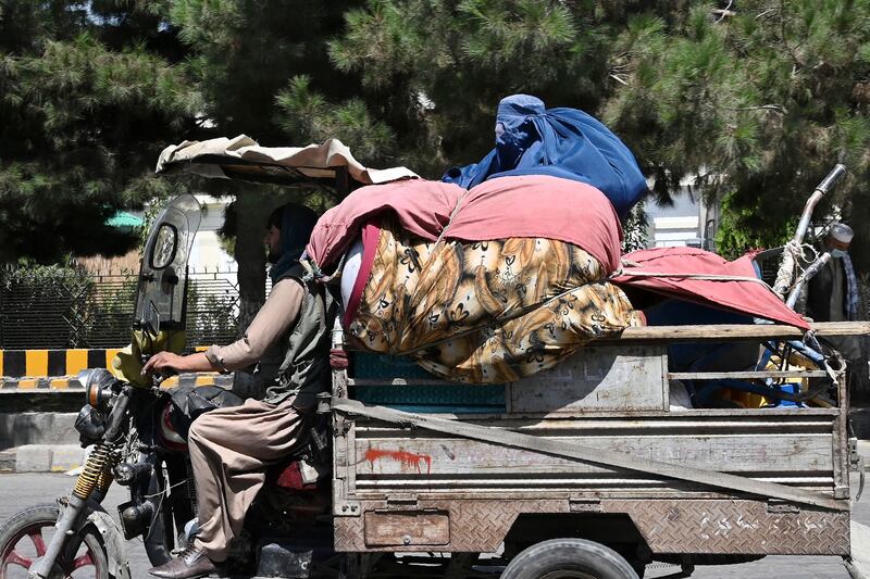 A burqa-clad woman rides at the back of a three-wheeler motorcycle cart in Kabul. AFP