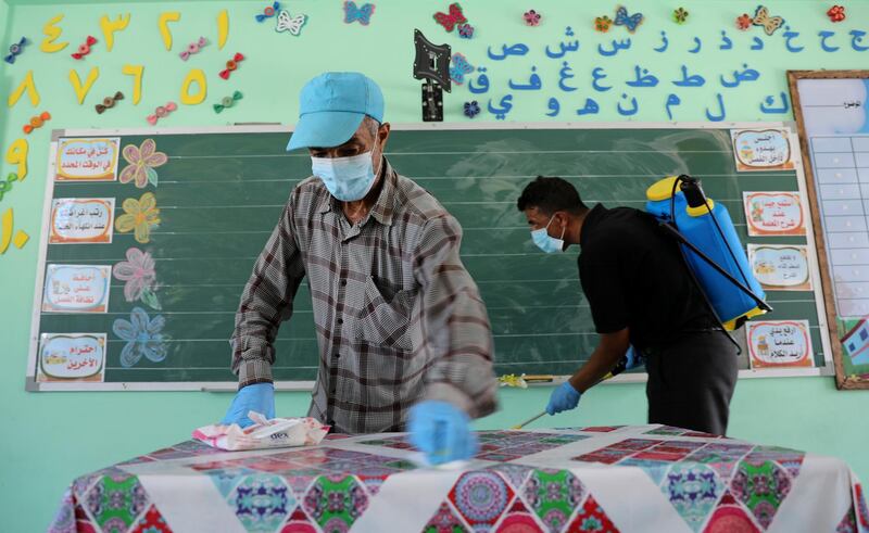 A Palestinian worker wearing a protective face mask cleans a table as another sanitises a classroom at a UN-run school before the start of new academic year, amid concerns about the spread of the coronavirus, in Gaza City. Reuters