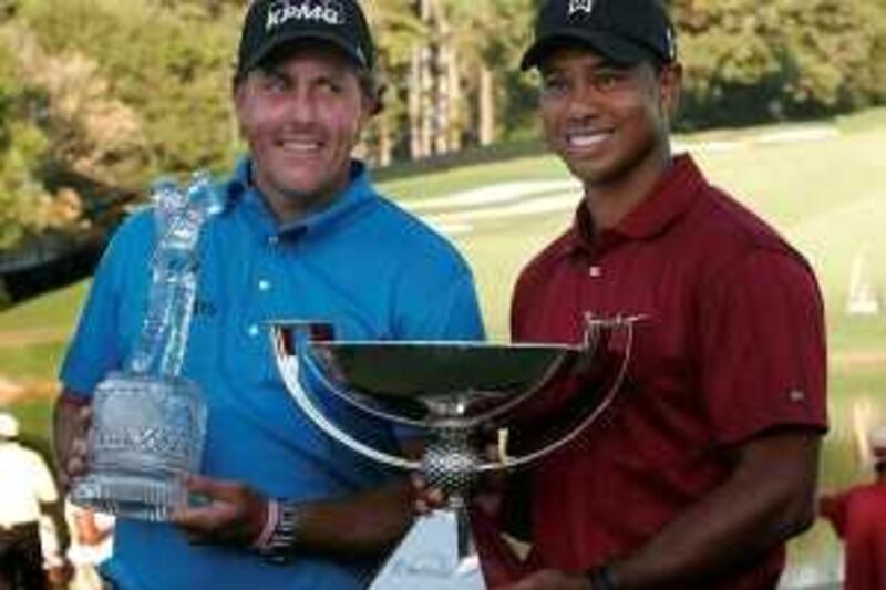 Phil Mickelson (L) of the U.S. looks over at his compatriot Tiger Woods as he holds the trophy after winning The Tour Championship golf tournament as Woods holds the FedEx trophy in Atlanta, Georgia, September 27, 2009. REUTERS/Steve Schaefer (UNITED STATES SPORT GOLF IMAGES OF THE DAY) *** Local Caption ***  ATL12_GOLF-_0927_11.JPG