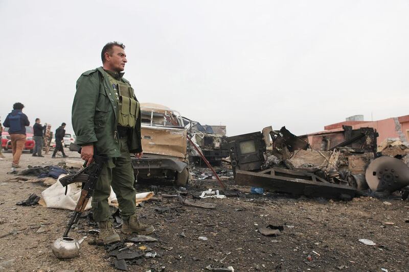 A member of the Kurdish forces stands in an area damaged by an improvised explosive device placed by ISIL militants that killed several Peshmerga fighters and injured dozens late Wednesday. Forces were inspecting the aftermath of the site in Kasr Reej, Iraq on December 18, 2014. Zana Ahmed/AP Photo