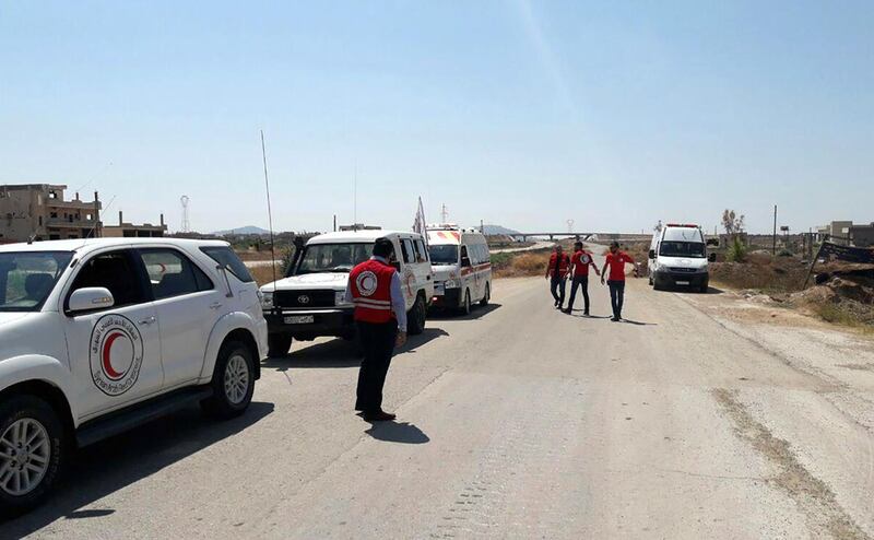 A handout picture released by the official Syrian Arab News Agency (SANA) shows members of the Syrian Red Crescent standing on a road, designated as the corridor for civilians to leave the opposition-held northwestern region of Idlib.  AFP