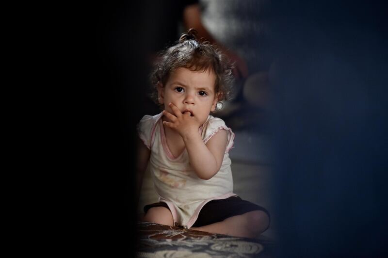 A toddler who suffers from scoliosis sits on the floor inside her tent at a Syrian refugee in Akkar, Lebanon. EPA