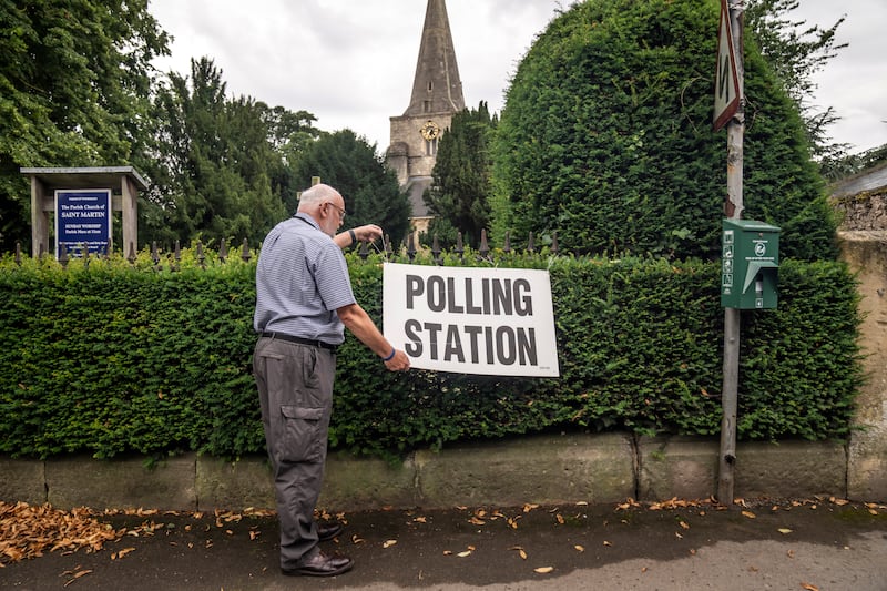 A man adjusts a polling station sign in Womersley, part of the Selby and Ainsty constituency, in North Yorkshire. PA
