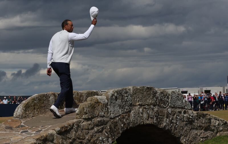 Tiger Woods acknowledges the fans as he walks over the Swilken Bridge. Reuters