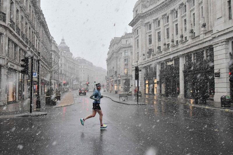 A jogger taking his daily exercise, crosses Regent Street in London in the snow, as the capital experiences a rare covering of snow on Sunday. AFP