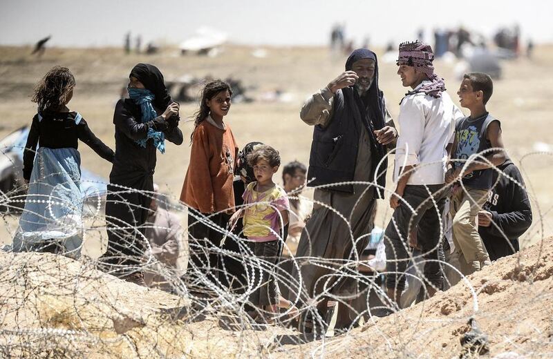 Syrian refugees gesture as they ask for water at the Turkish border near the Syrian town of Tal Abyad, on June 13. AFP PHOTO 

