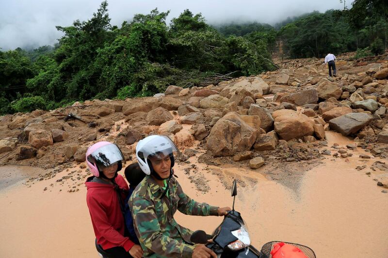 People ride a motorcycle past an area affected by landslide in Attapeu province, Laos. Reuters