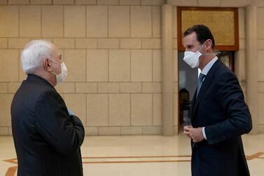 Syria's President Bashar al-Assad and Iran's Foreign Minister Mohammad Javad Zarif, wearing face masks as protection against the spread of the coronavirus disease (COVID-19), meet in Damascus, Syria, in this handout released by SANA on April 20, 2020. SANA/Handout via REUTERS