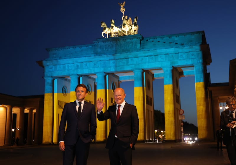 Olaf Scholz and French President Emmanuel Macron stand in front of the Brandenburg Gate in Berlin, illuminated in the colors of the Ukrainian flag in May. Getty Images