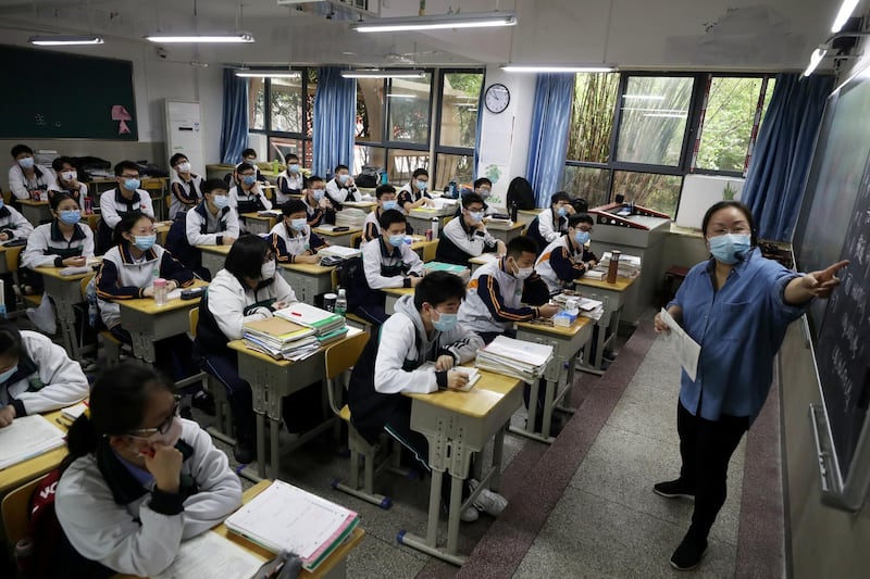 A teacher and senior high school pupils wearing face masks are seen inside a classroom on their first day of returning to school in Wuhan, Hubei province, China.  Reuters