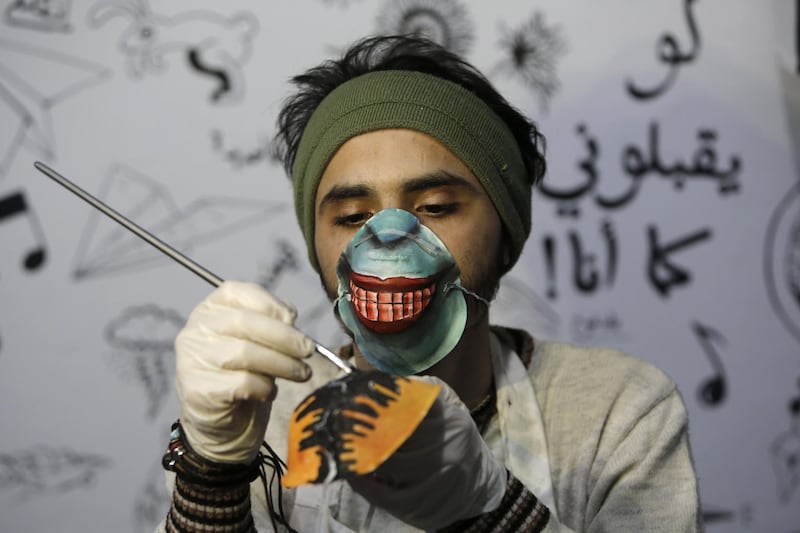 Palestinian artist Dorgham Krakeh paints a dust mask for a project raising awareness about the COVID-19 coronavirus pandemic, in Gaza City.   AFP