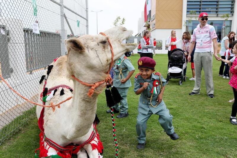 Mohammed Ismail, 5, tries to sneak up on a camel during National Day activities at Cranleigh school in Abu Dhab. Christopher Pike / The National