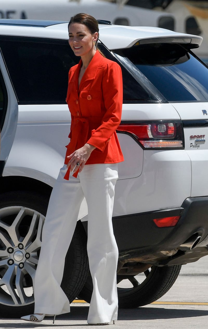 Catherine wears a vintage red YSL jacket and white trousers to board the plane in Belize on March 22. AFP