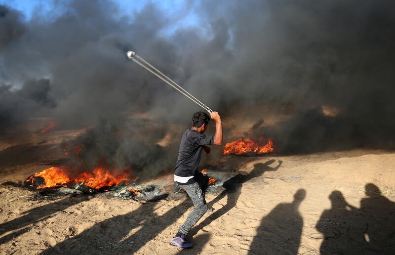 A Palestinian protester uses a slingshot next to burning tyres during a demonstration at the Israel-Gaza border, east of Khan Yunis in the southern Gaza Strip. AFP