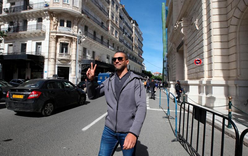 Algerian journalist Khaled Drareni flashes the V sign as he leaves the courthouse in Algiers on March 10, 2020. Khaled Drareni , who played a prominent role in covering the country's pro-democracy movement last year was sentenced Monday Aug.10, 2020 to three years in prison for inciting unauthorized demonstrations and attacking national unity. (AP Photo/Str)